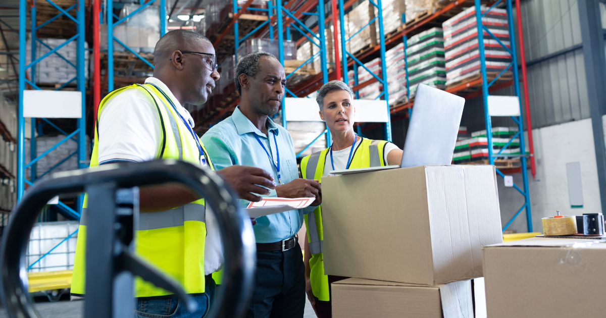 employees in a warehouse looking at a laptop